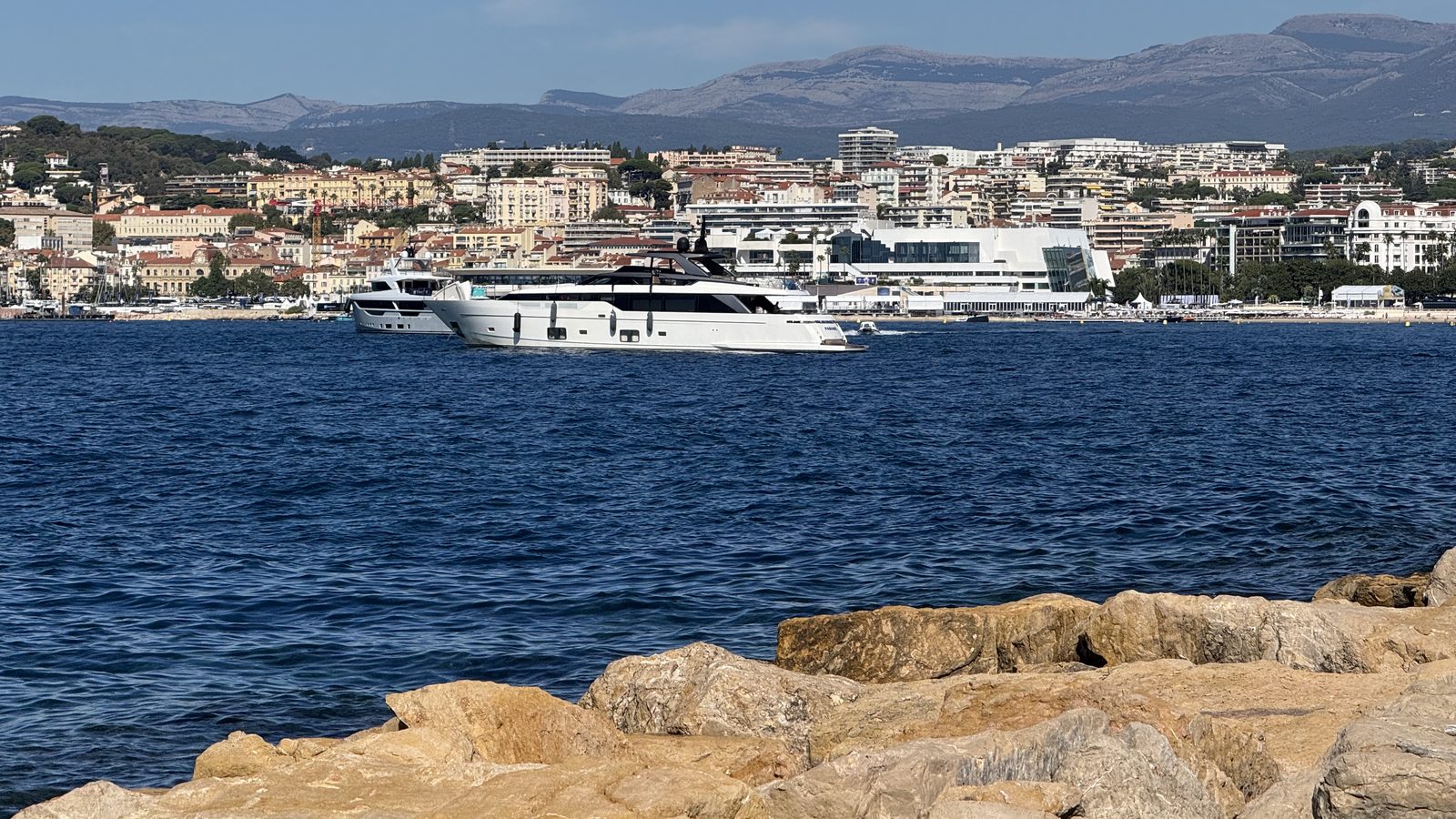 Two motor yachts under way in front of a coastal town