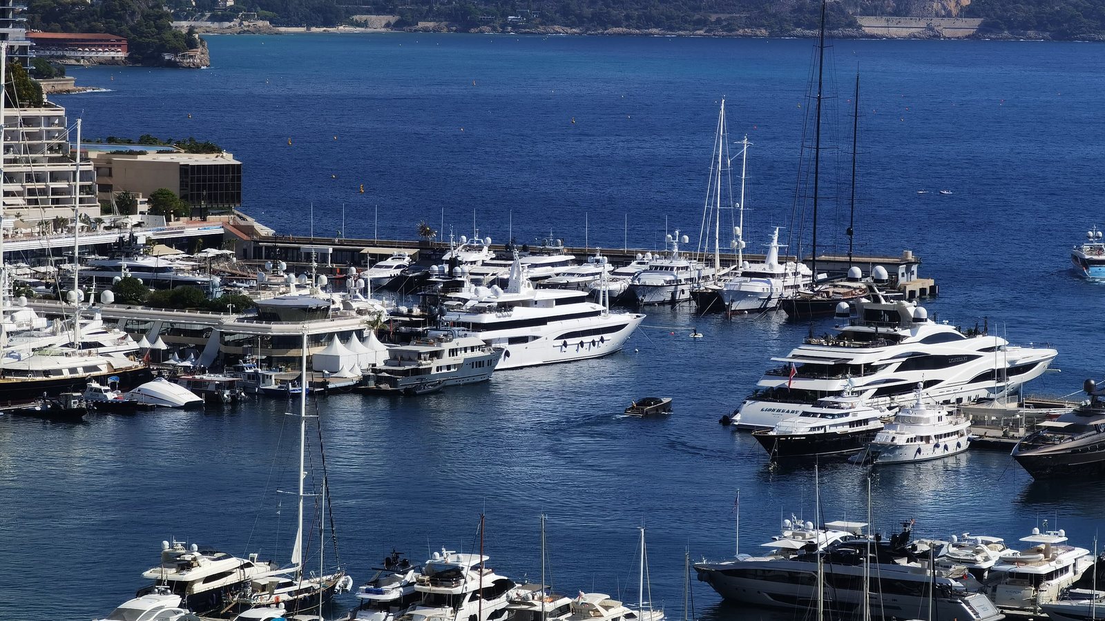A harbour full of superyachts and motor yachts below a hillside town