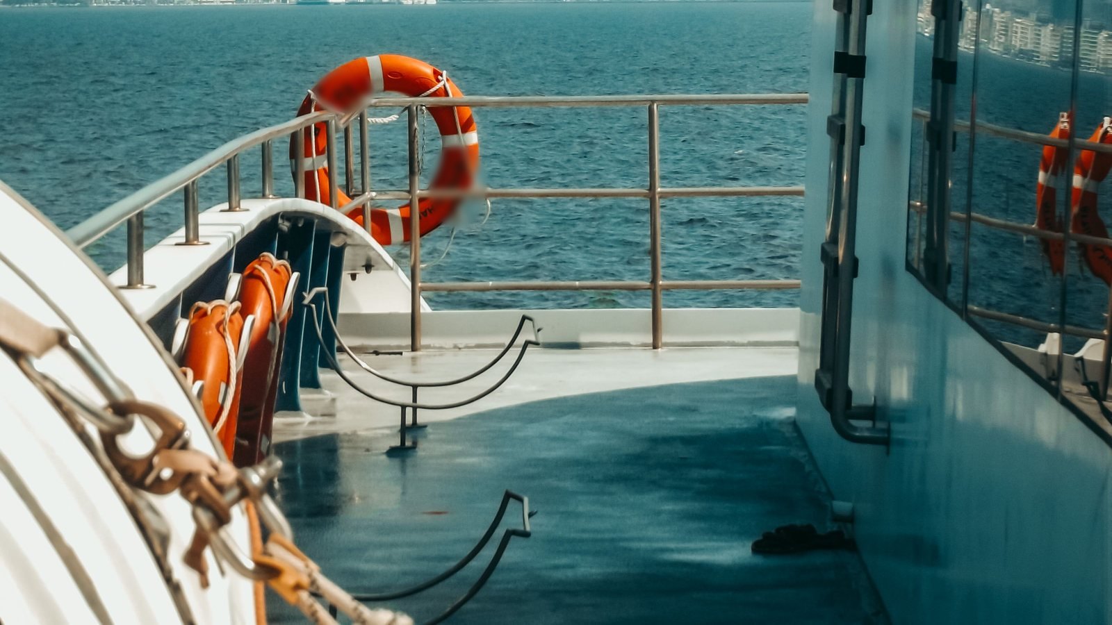 Lifebuoy hanging on the rail at the stern of a vessel, deck and open water behind