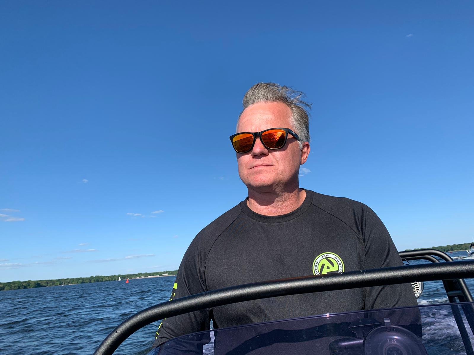 Andreas Lakeberg in sunglasses at the helm of a motor boat on open water